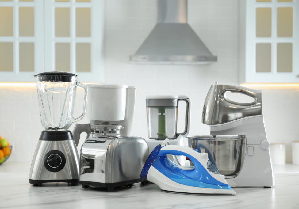 Set of modern home appliances on white marble table in kitchen